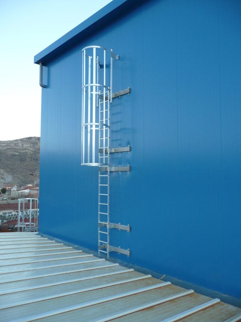 Escalera vertical fija instalada en entorno industrial conforme a normativa de seguridad y acceso en altura